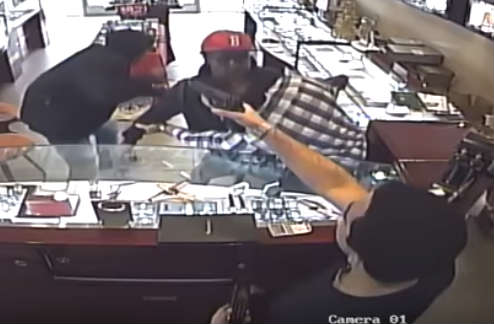 Store owner's nephew grabs a handgun and points it at the culprits. Video surveillance shows one of the suspects ducking, before running out of the store.
