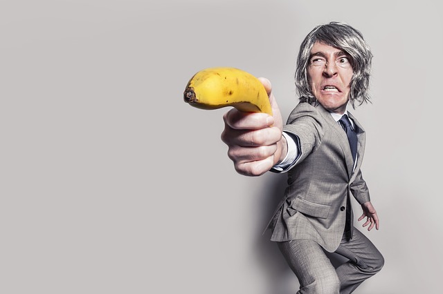 Man in suit pulls banana out and points it like a gun.